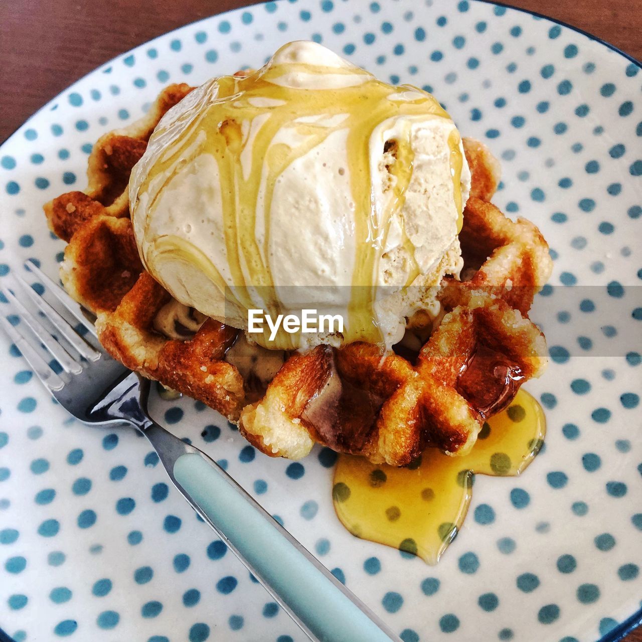 High angle view of waffle with ice cream and honey in plate