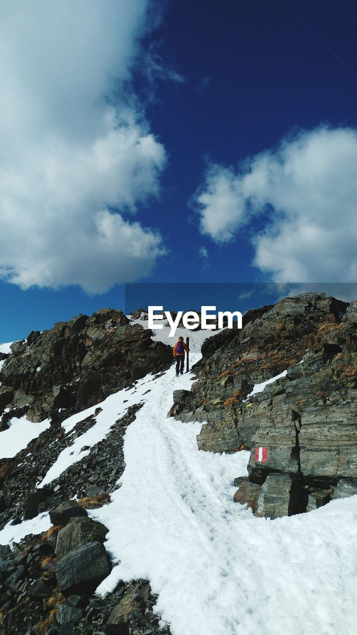 PEOPLE ON CLIFF AGAINST MOUNTAIN DURING WINTER