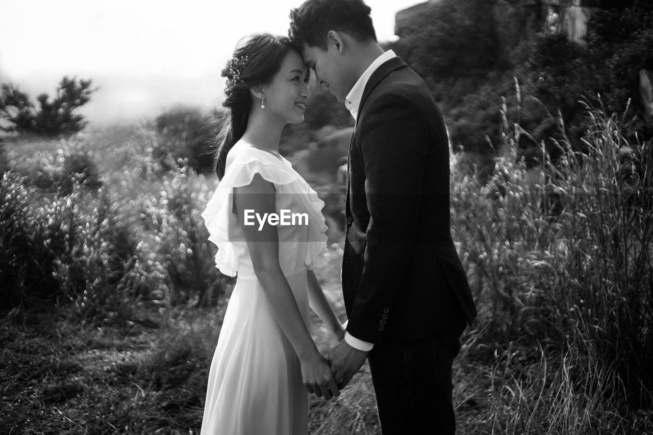 Side view of newlywed couple with face to face standing in park