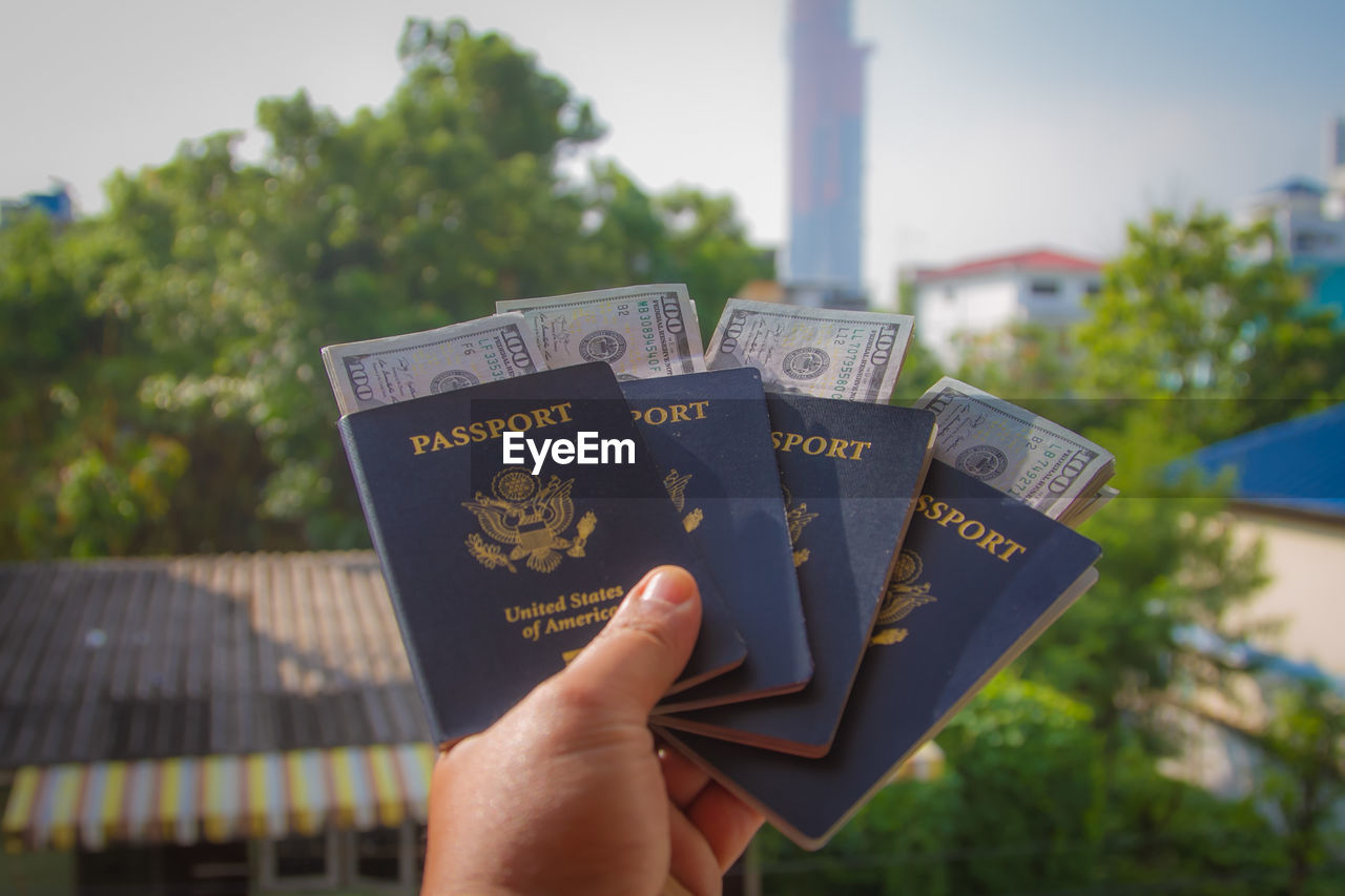 Cropped hand holding passports and paper currency in city