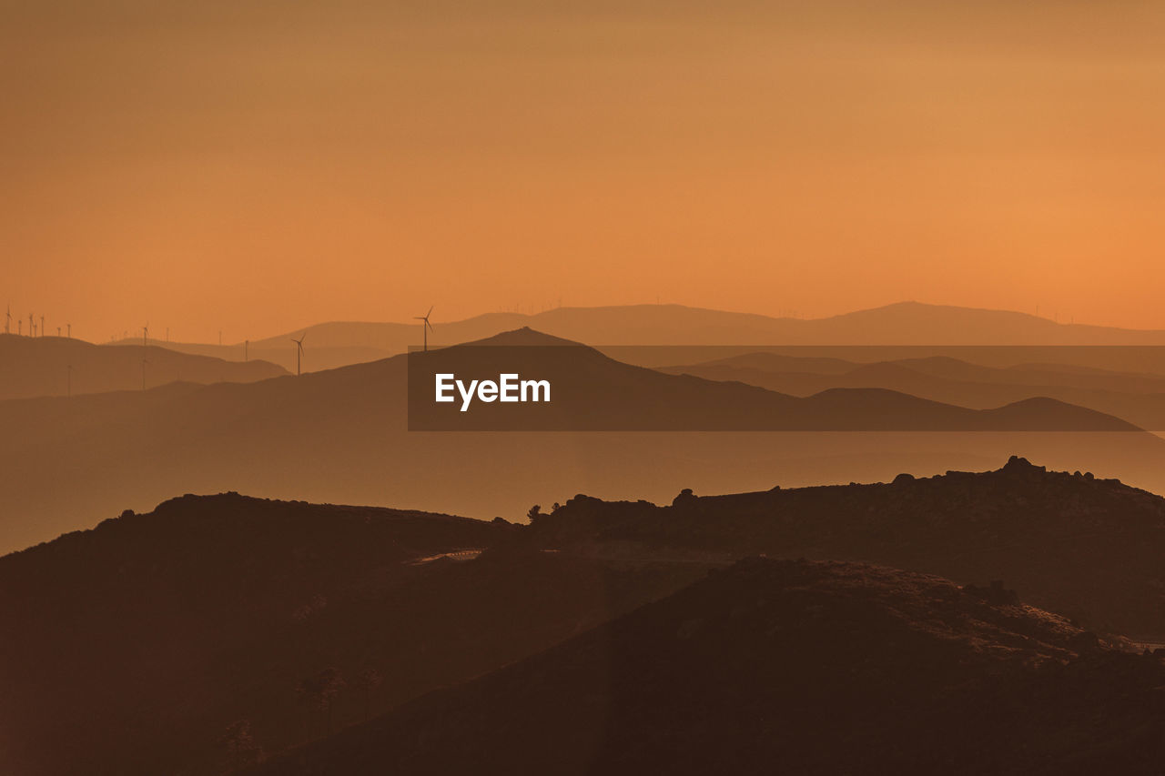 scenic view of silhouette mountains against orange sky