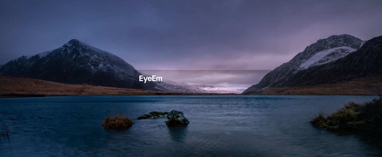 Scenic view of lake by mountains against sky