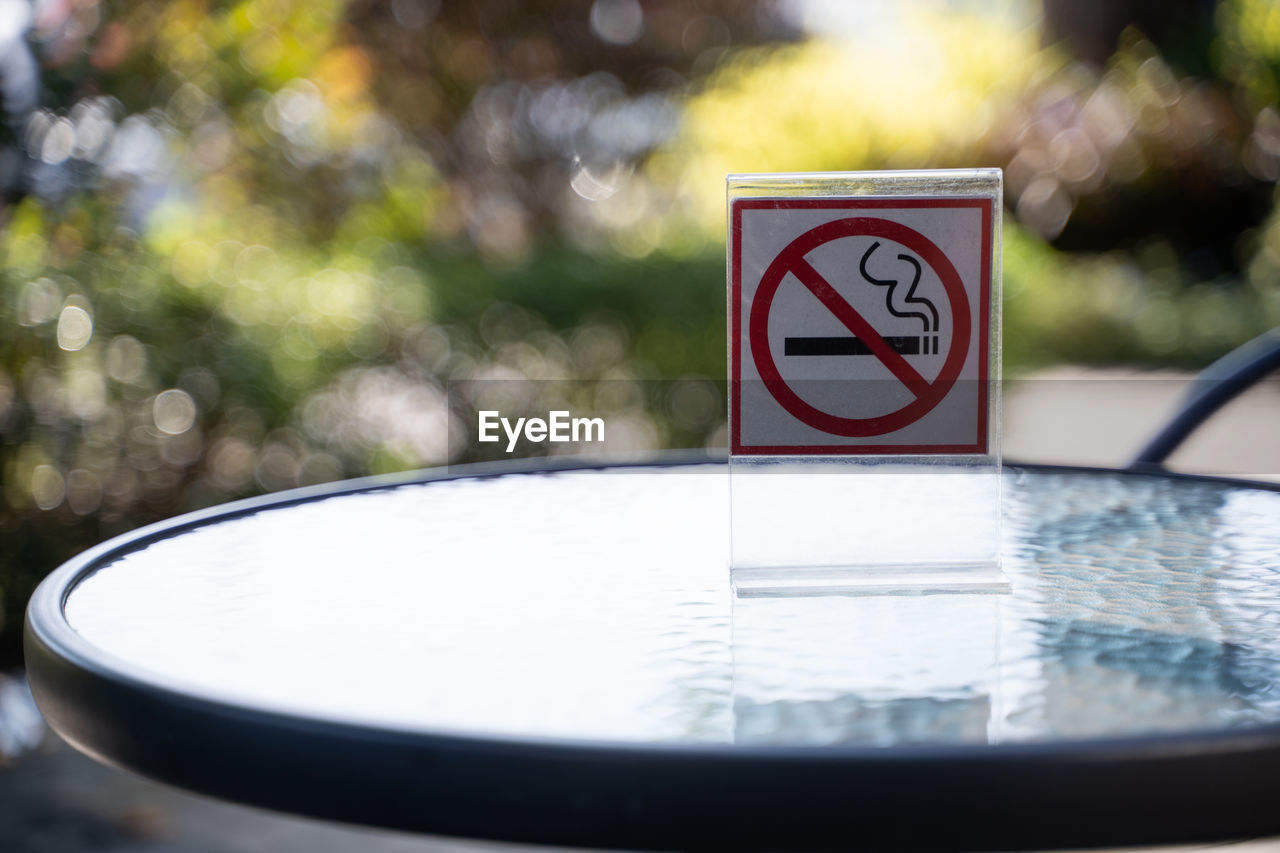 Close-up of no smoking sign on glass table at sidewalk cafe