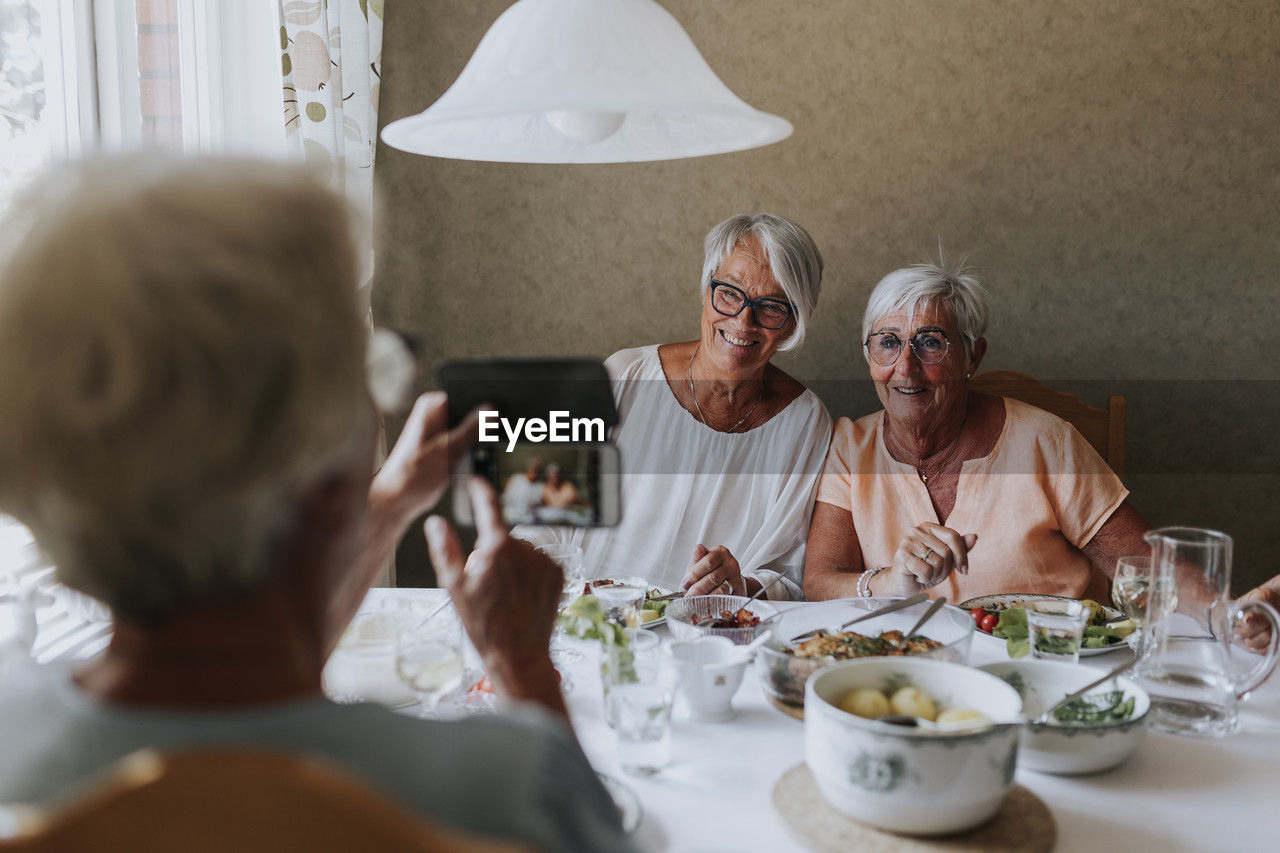 Senior women having picture taken while having meal together