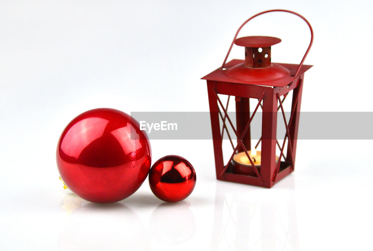 CLOSE-UP OF RED LAMP ON TABLE AGAINST WHITE BACKGROUND