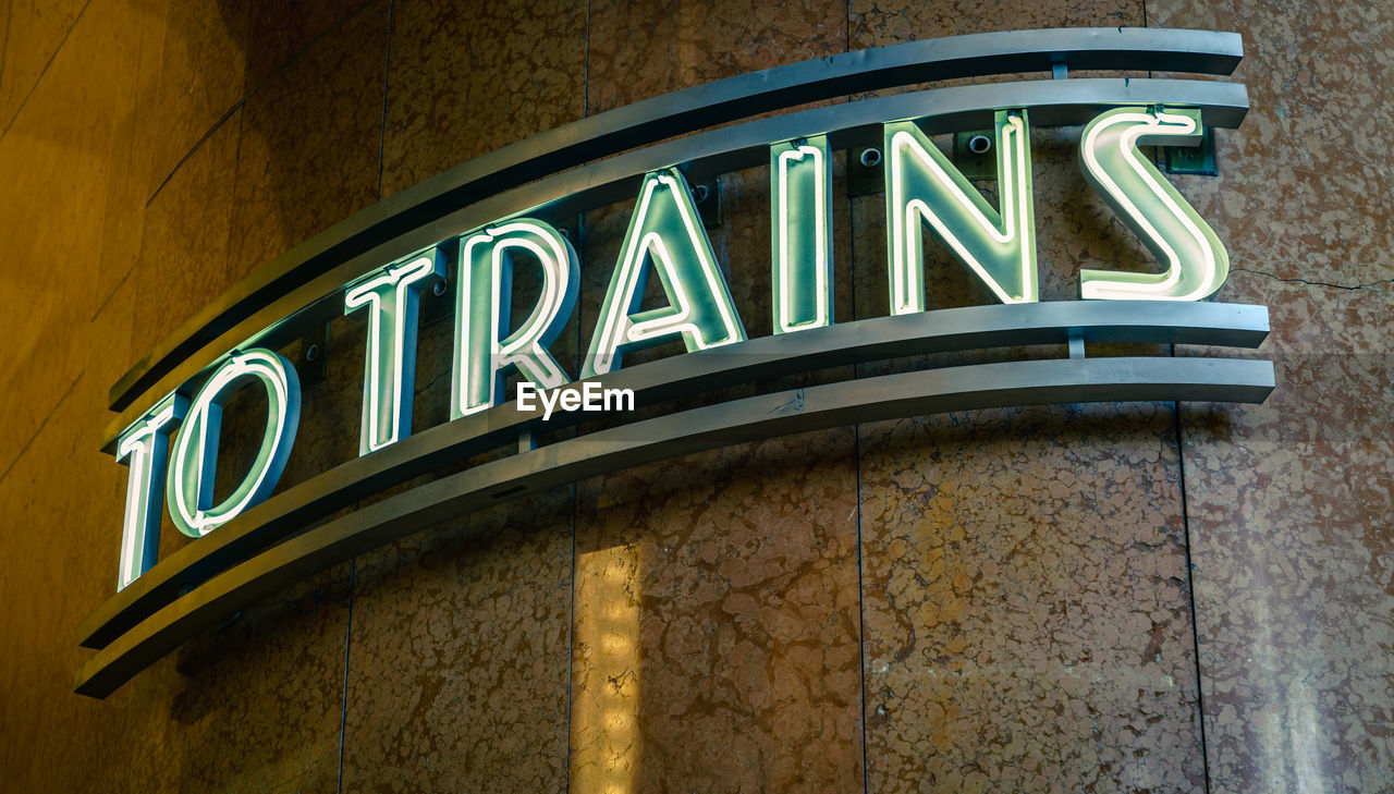 LOW ANGLE VIEW OF ILLUMINATED SIGN ON WALL AT NIGHT