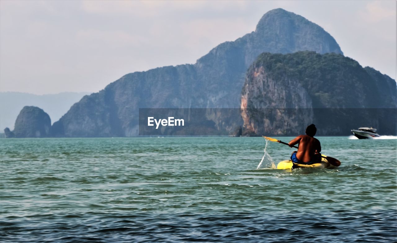 Man on boat in sea against mountains