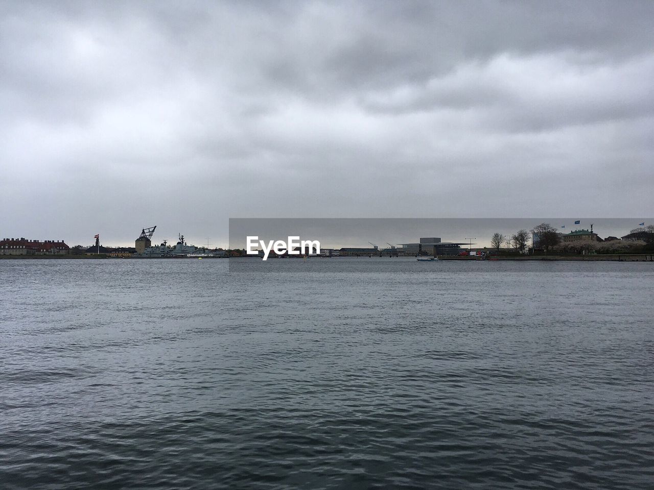 VIEW OF CITY BY SEA AGAINST STORM CLOUDS