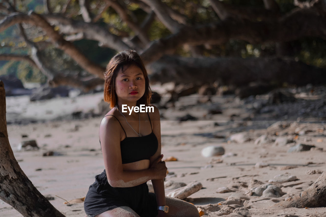 Portrait of young woman sitting on shore at beach