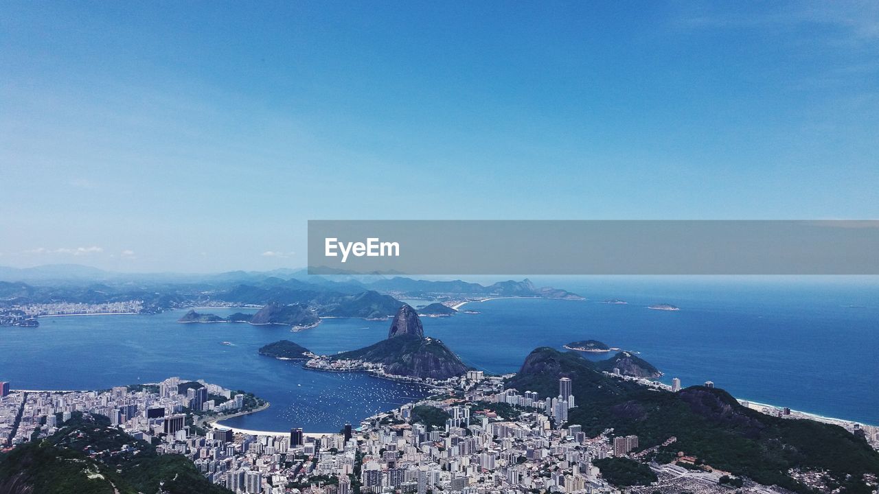 HIGH ANGLE VIEW OF SEA AND CITY BUILDINGS AGAINST SKY