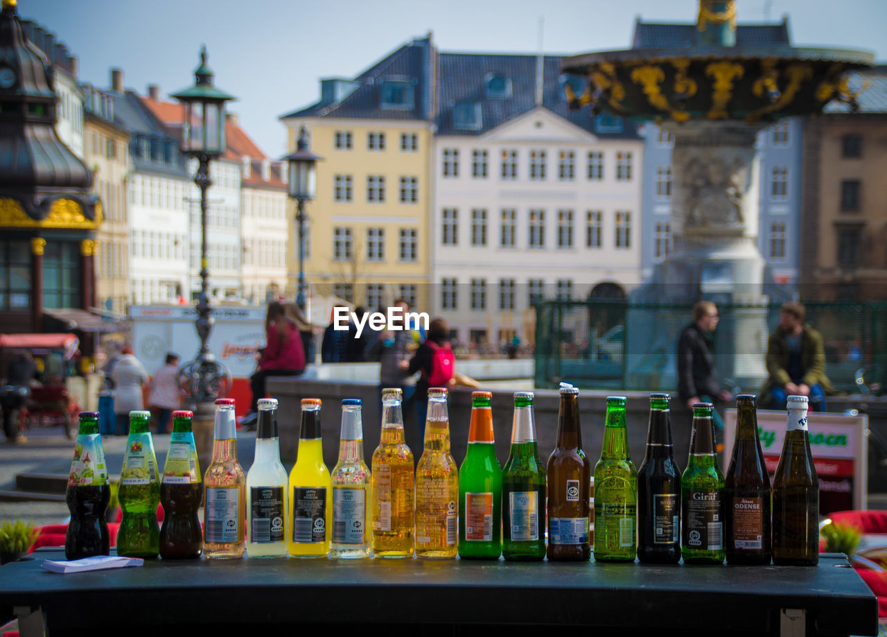 Bottles arranged on table against buildings in city