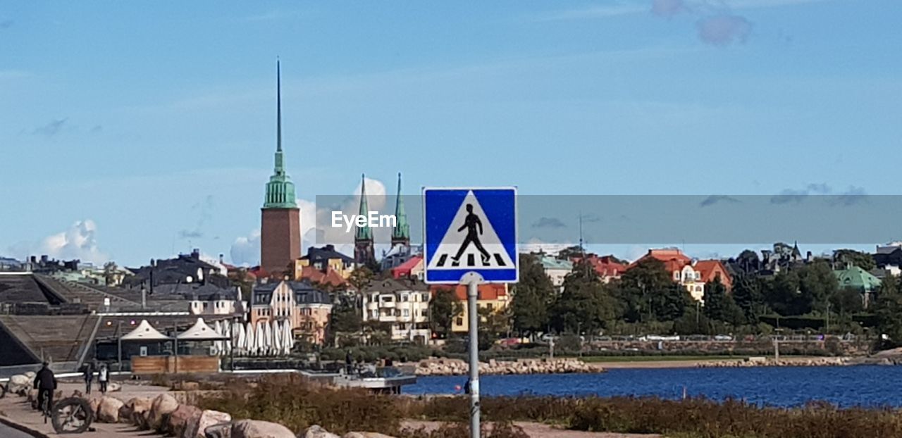 VIEW OF ROAD SIGN BY BUILDINGS AGAINST SKY
