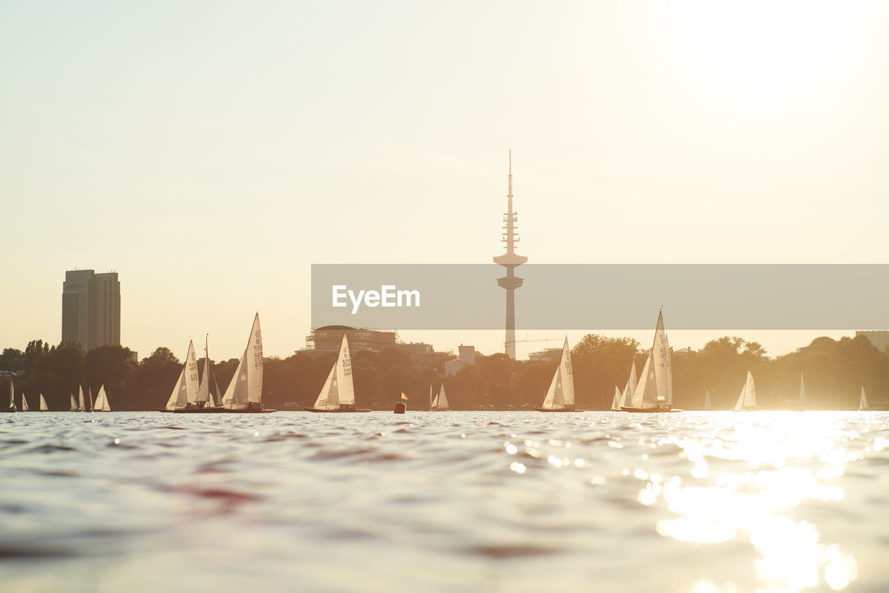 Water surface image of boats moving on river against sky during sunset