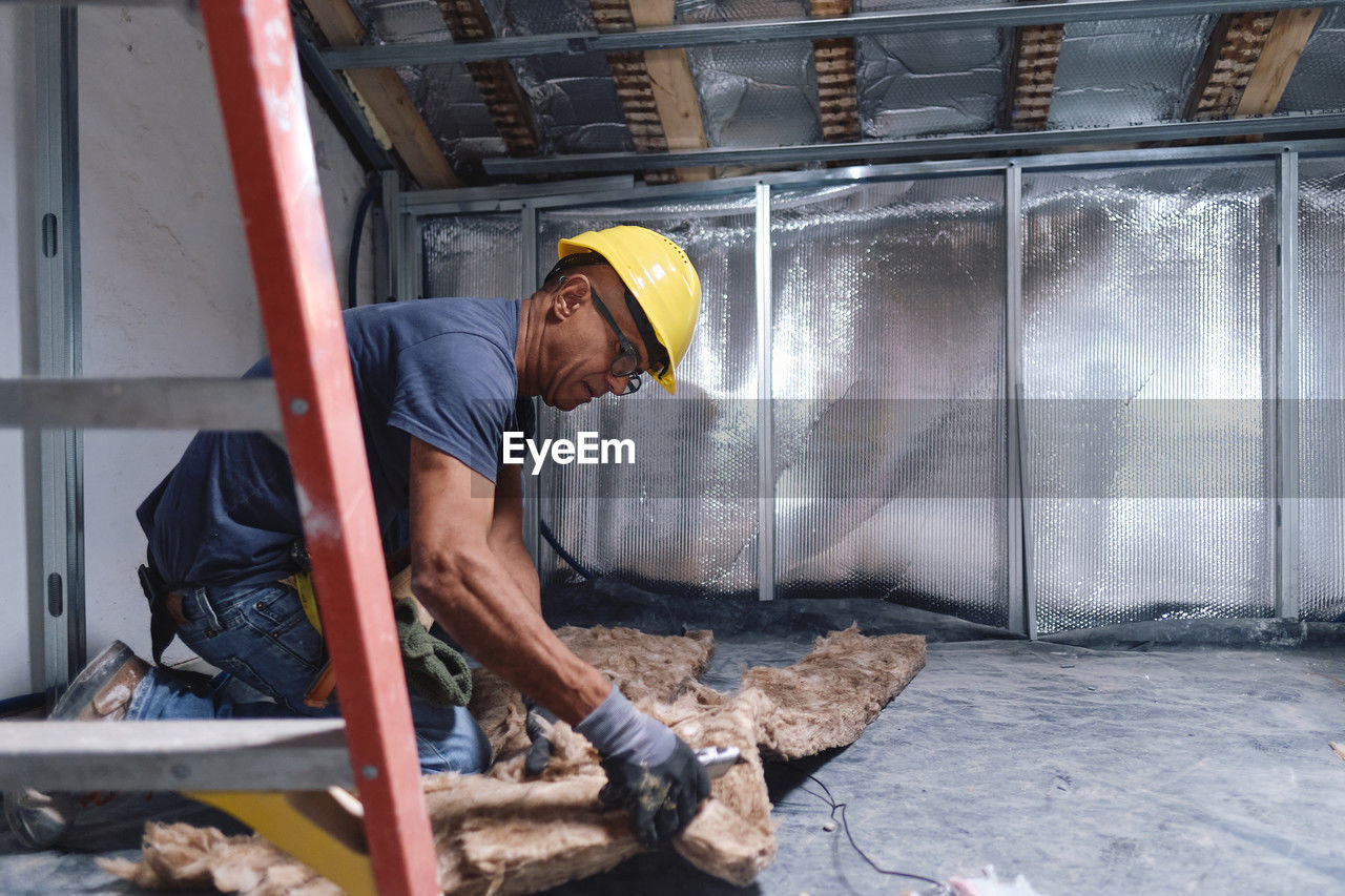 Mature construction worker working on insulation at site