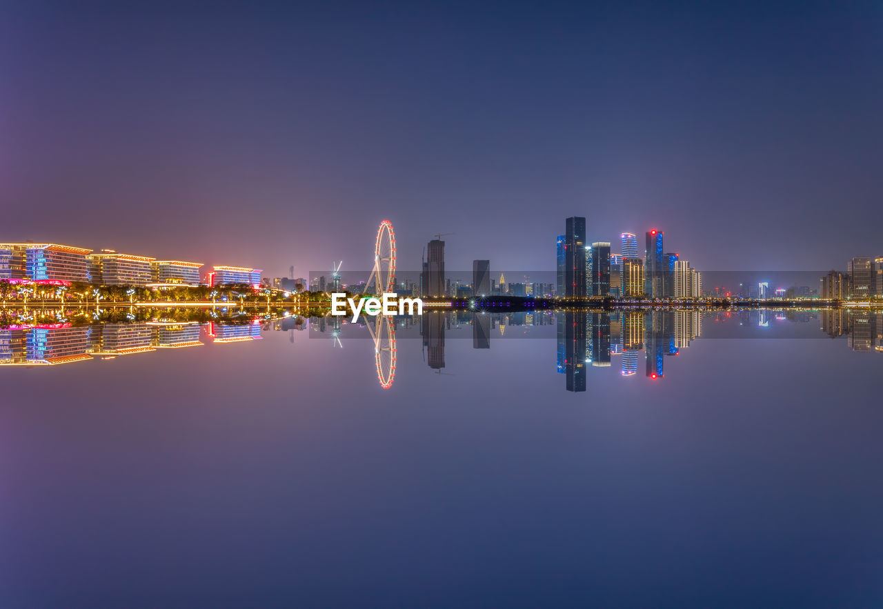 ILLUMINATED MODERN BUILDINGS AGAINST CLEAR SKY AT NIGHT