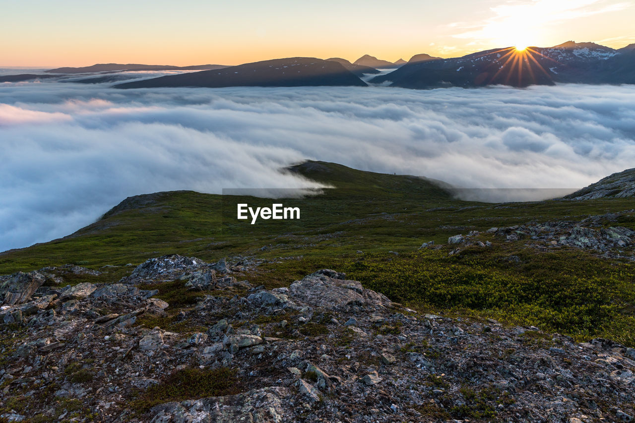 Clouds covering mountains against sky during sunrise