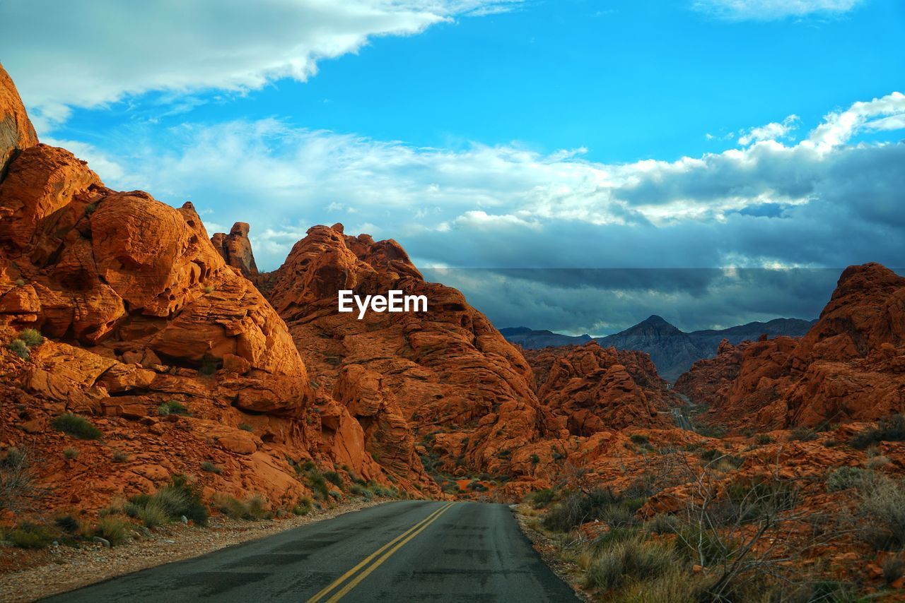 Road leading towards mountains against sky