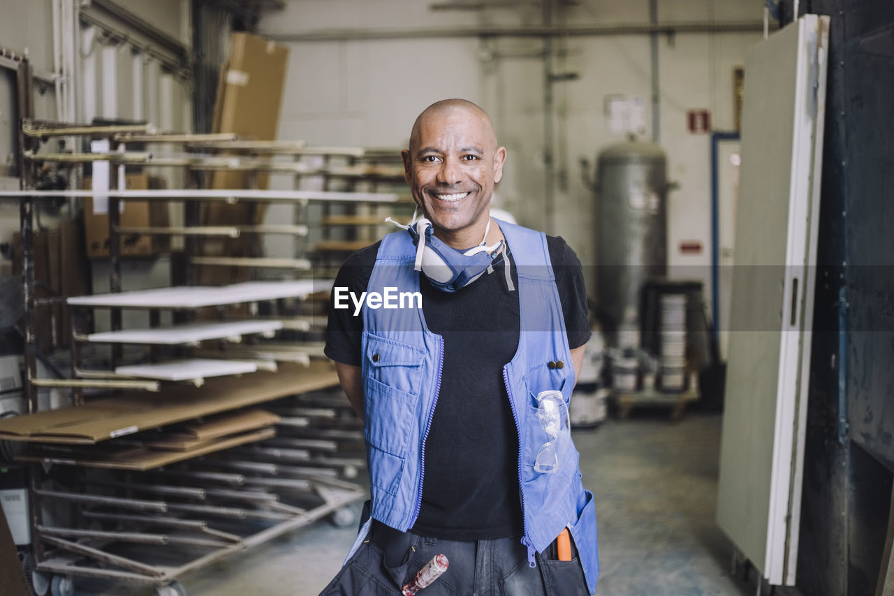 Portrait of smiling bald painter standing in workshop