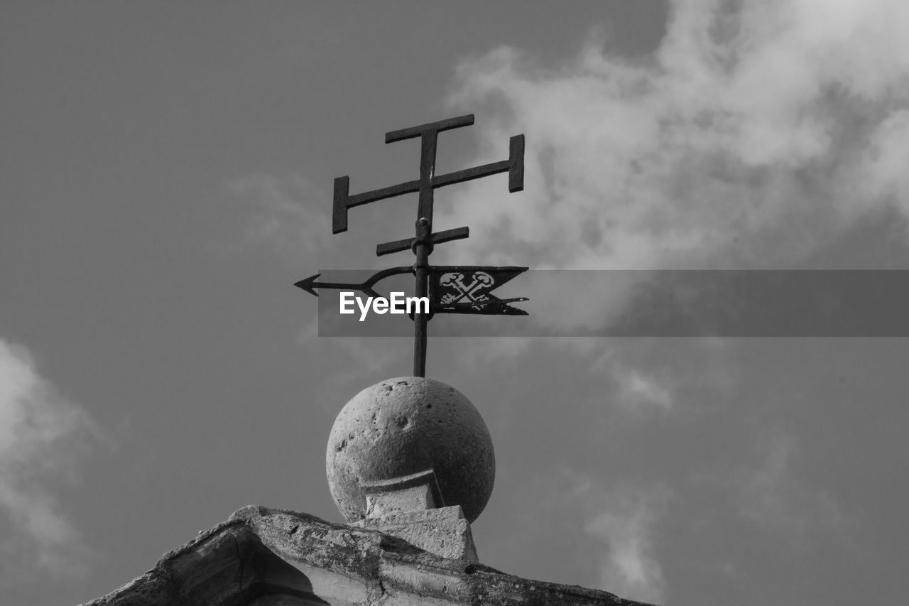 Low angle view of cross sculpture against sky