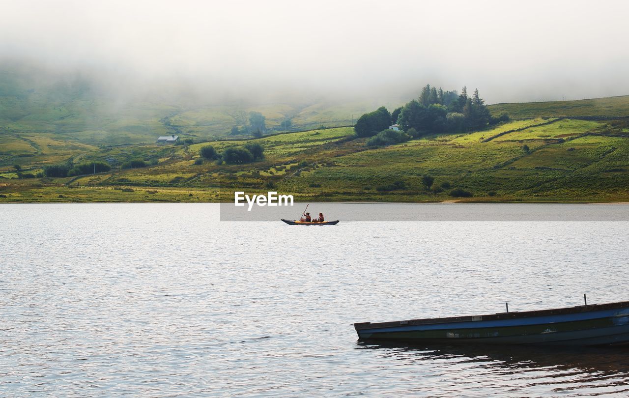 People canoeing on loch na fooey, sandy beach, green mountains, landscape of connemara,county galway