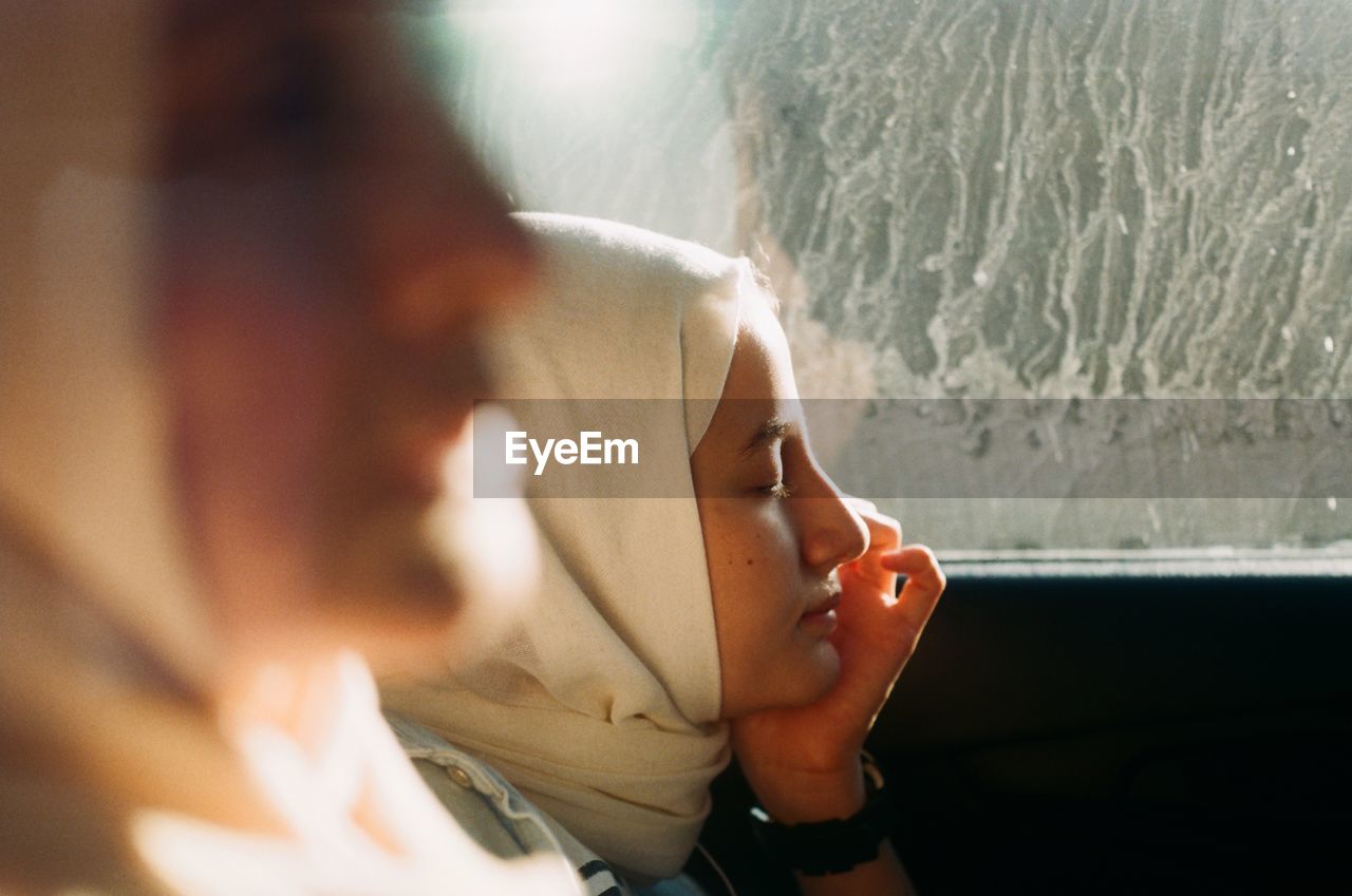 Close-up of young women sitting against window