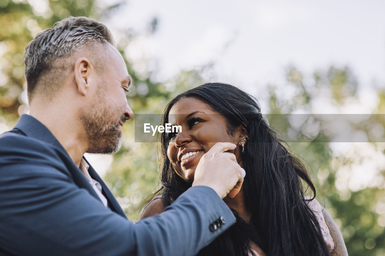 Smiling affectionate mature groom touching young bride's cheek