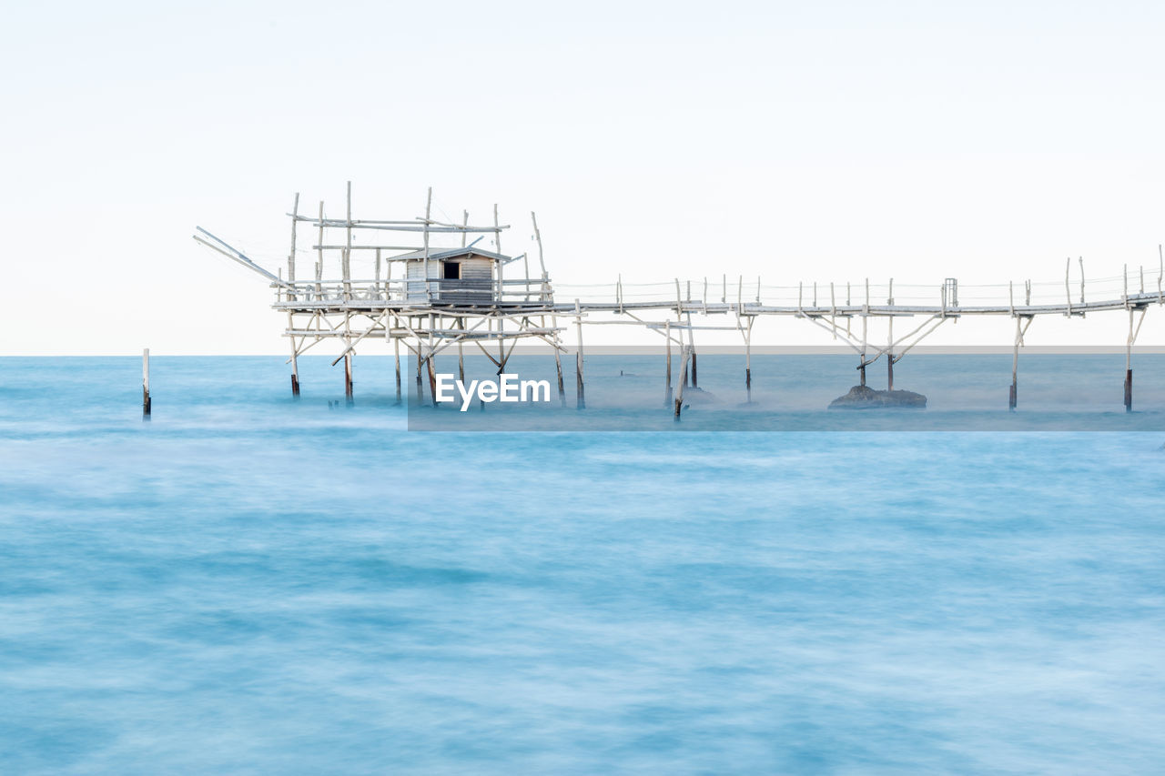 Pier over sea against clear blue sky