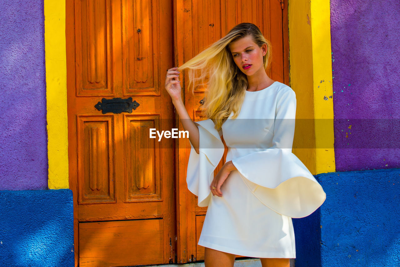 YOUNG WOMAN LOOKING AWAY WHILE STANDING ON DOOR