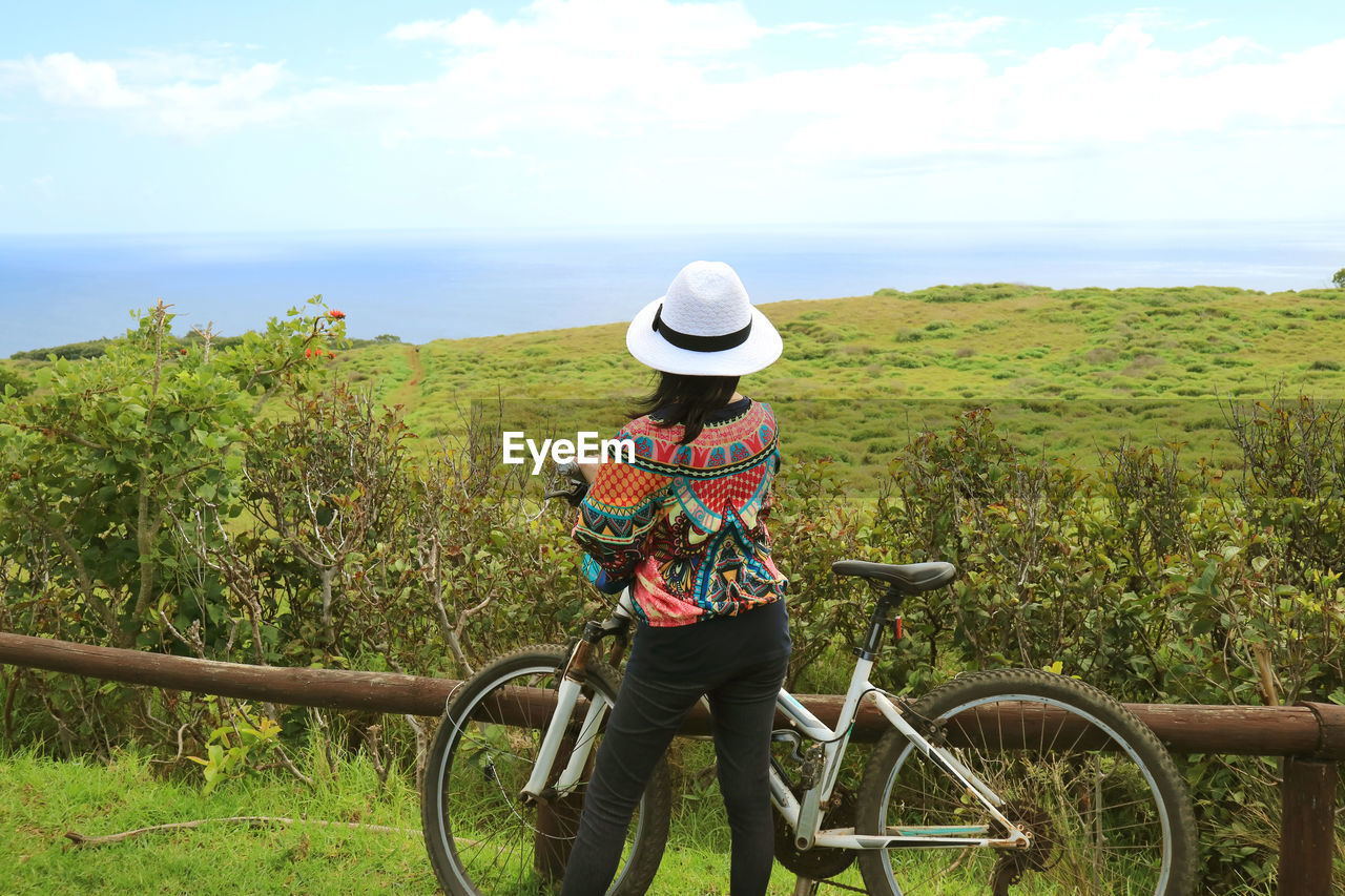 Rear view of person with bicycle on sea against sky