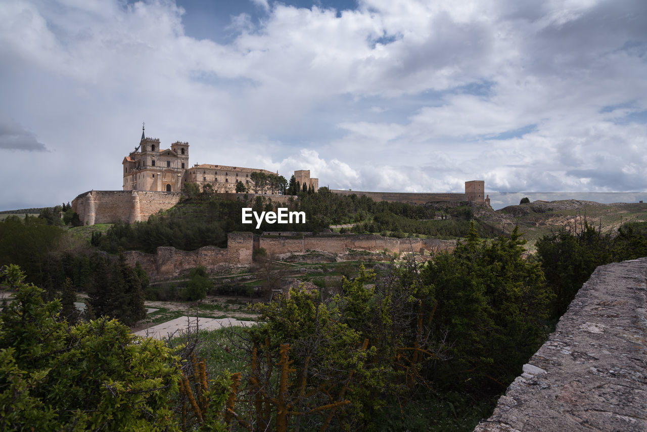 Panoramic view of the monastery, the castle and the walls of ucles against a cloudy sky, cuenca