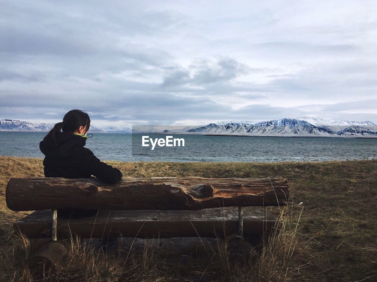 MAN SITTING ON SHORE AGAINST SEA