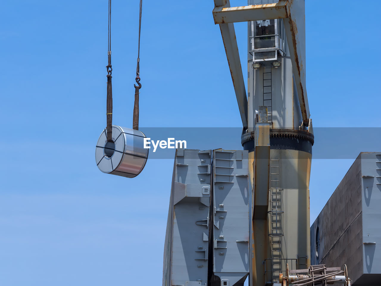 Low angle view of crane against clear blue sky