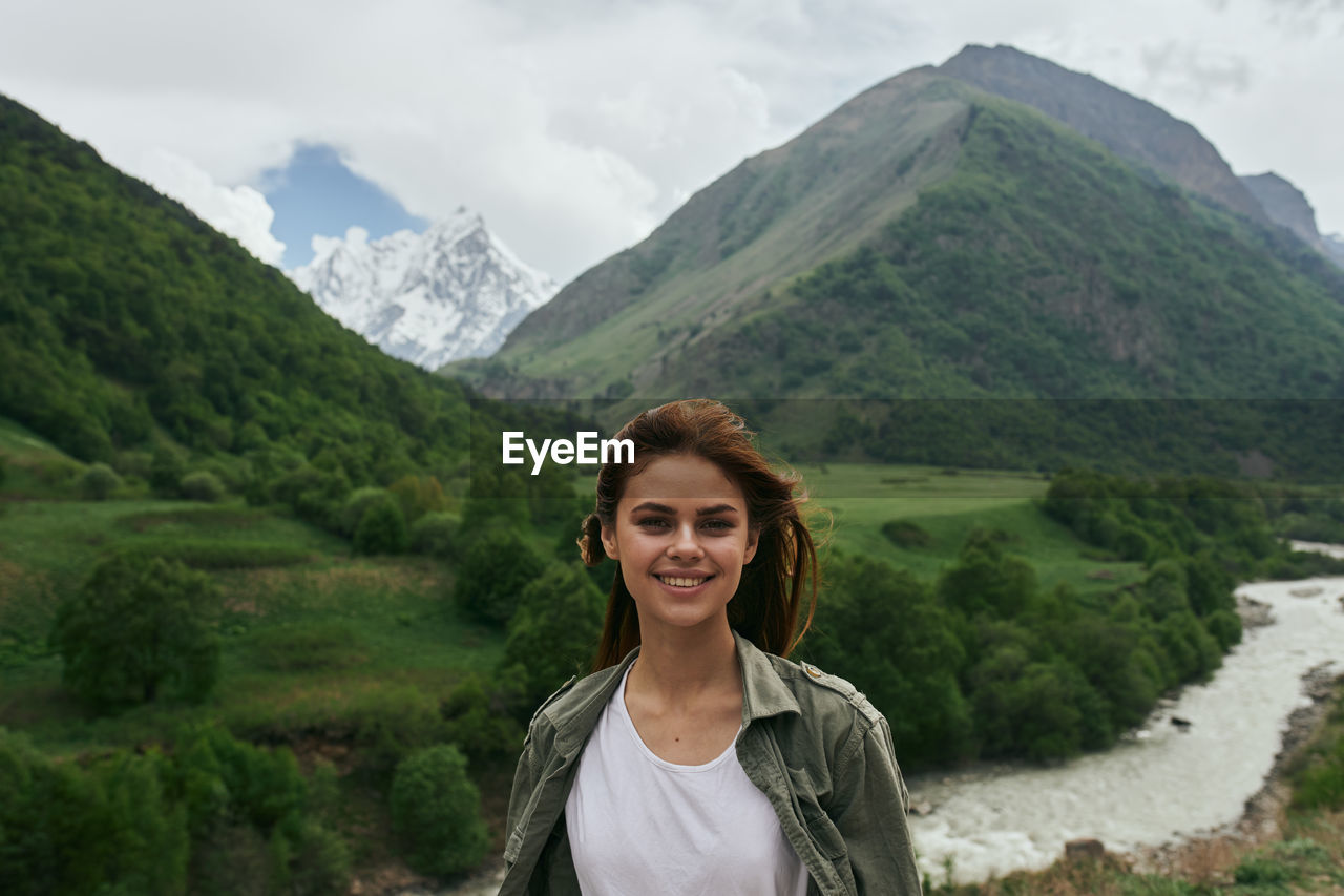 portrait of young woman standing against mountains