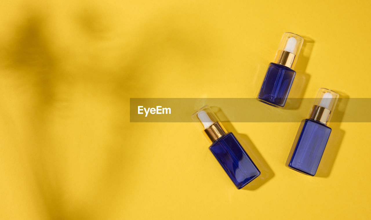 Glass cosmetic blue bottles with a pipette on a yellow background. cosmetics spa branding mockup, 