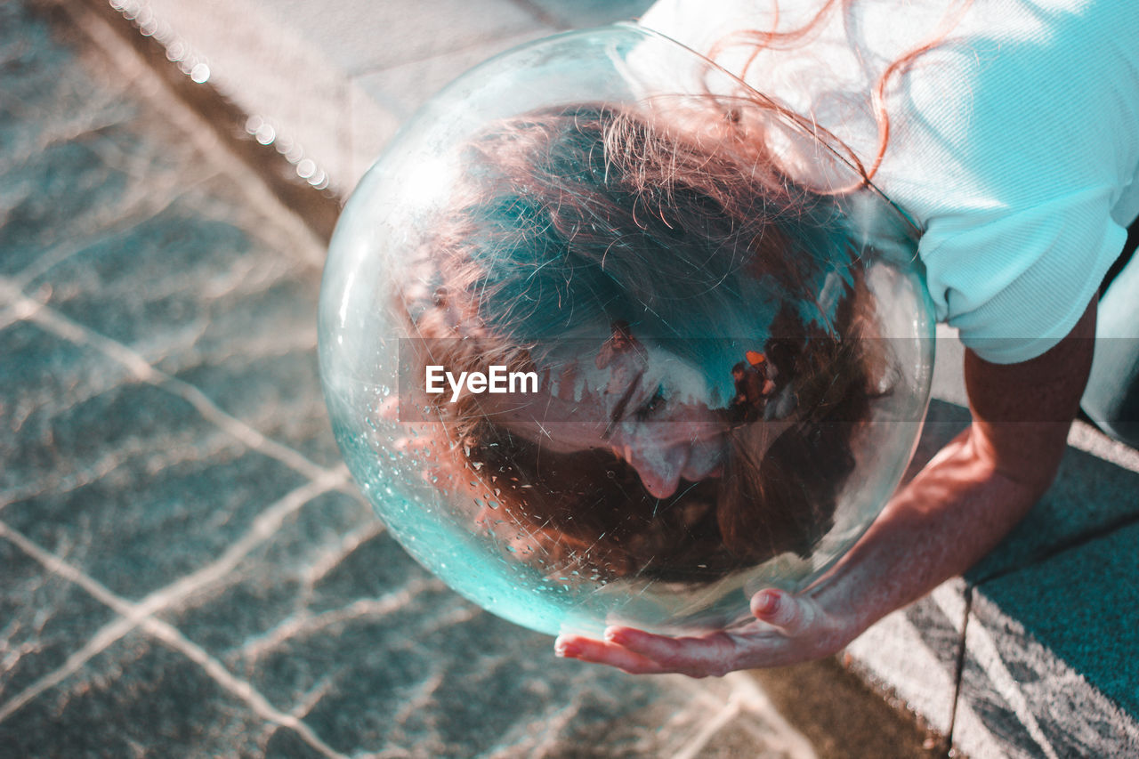 Close-up of woman wearing glass container at lake