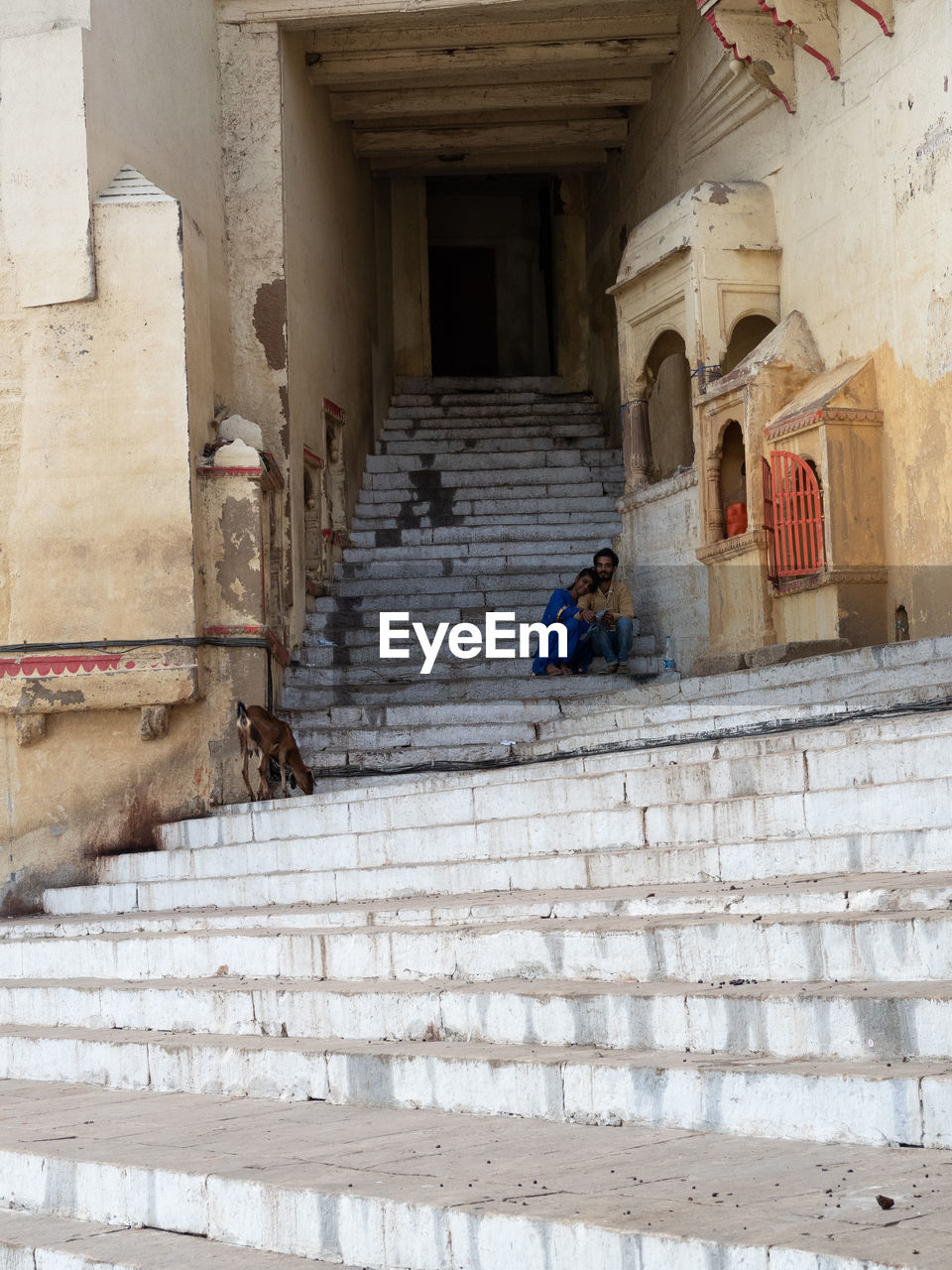 REAR VIEW OF WOMAN WALKING ON STAIRCASE BY BUILDING