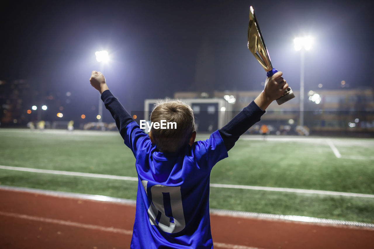 Young soccer player in blue jersey with ten number holding  winners cup after winning goal