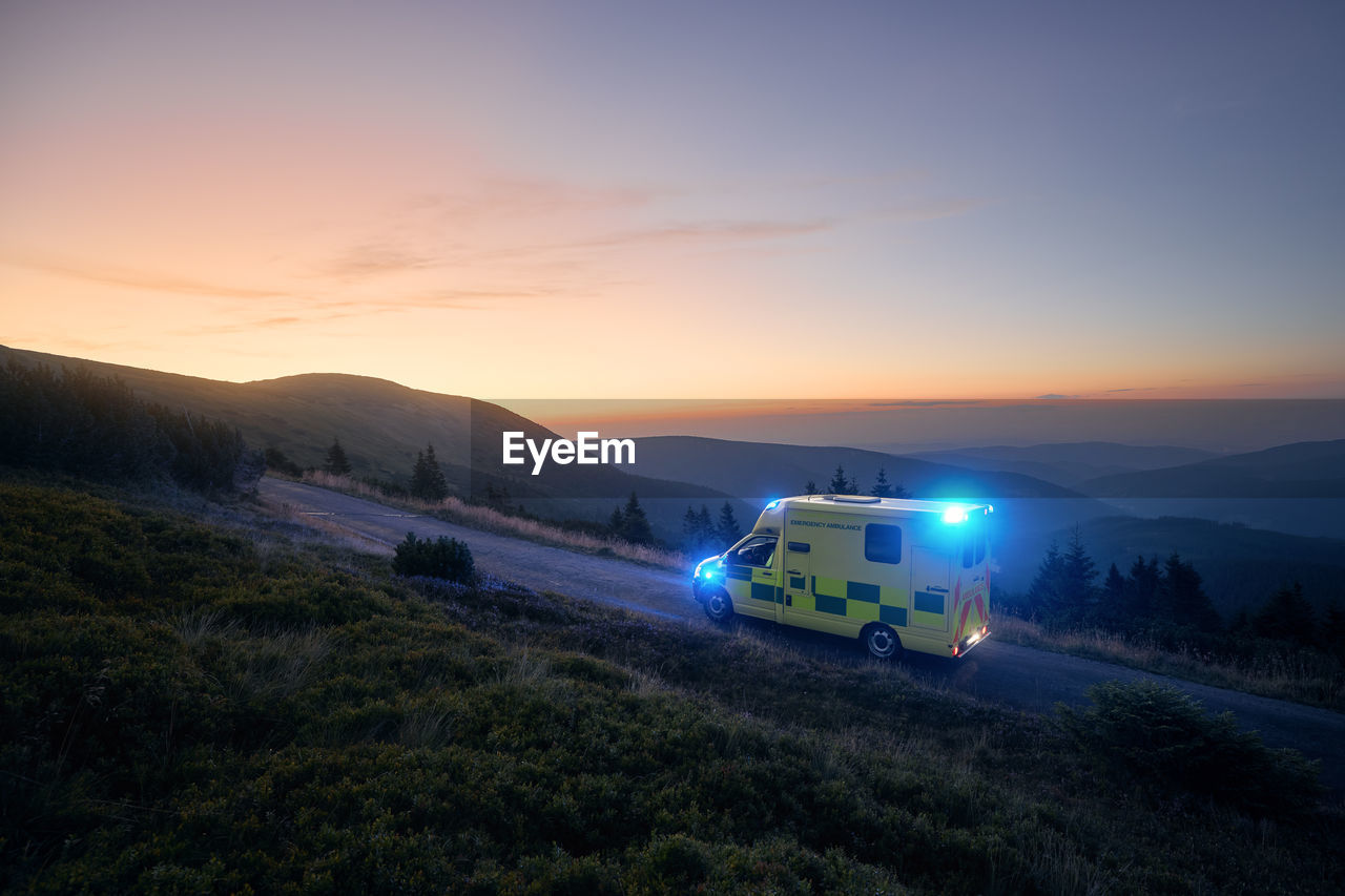 Ambulance car of emergency medical service mountain road against sunrise. moody sky with copy space. 