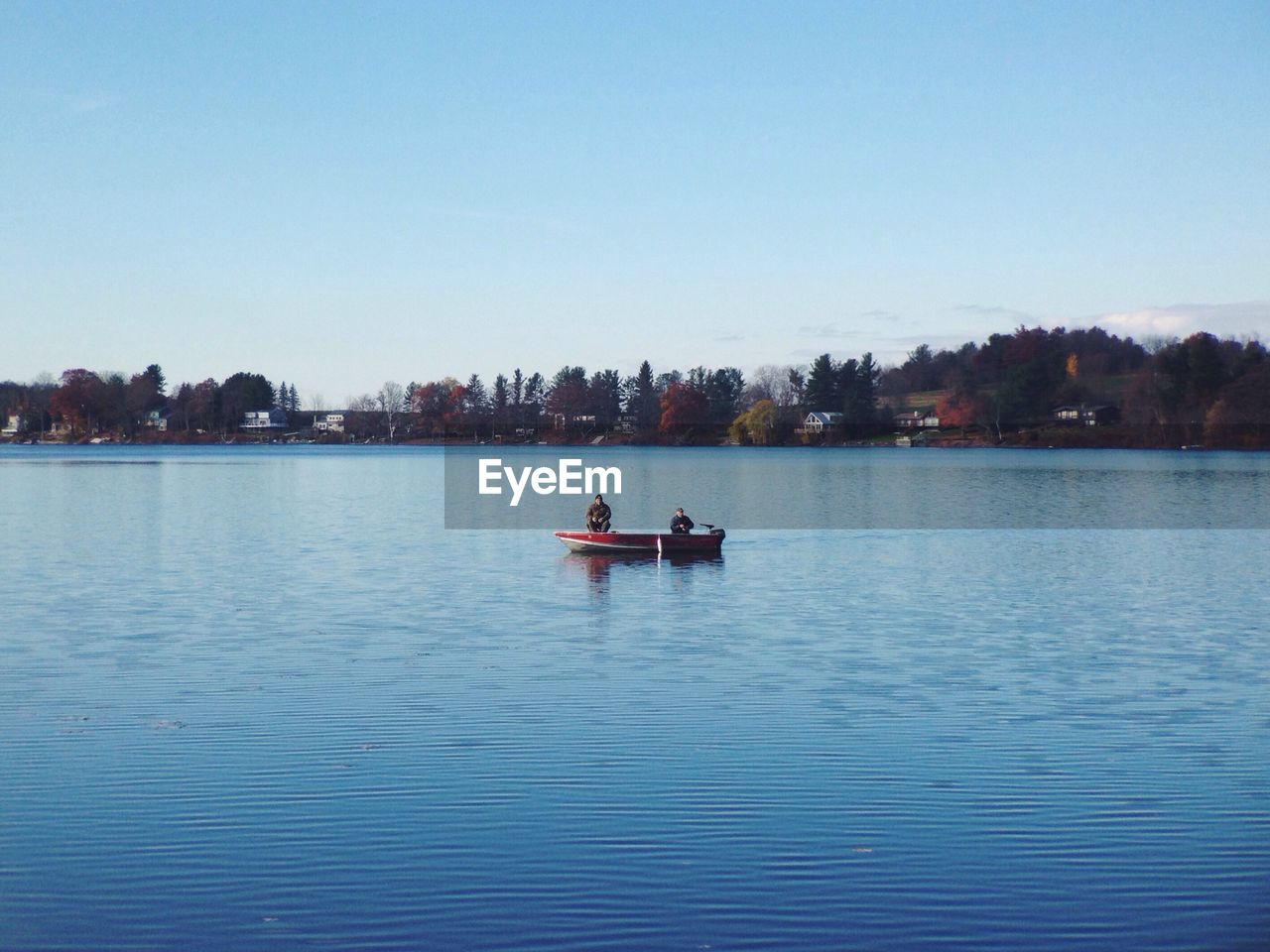 Boat sailing on lake against clear blue sky