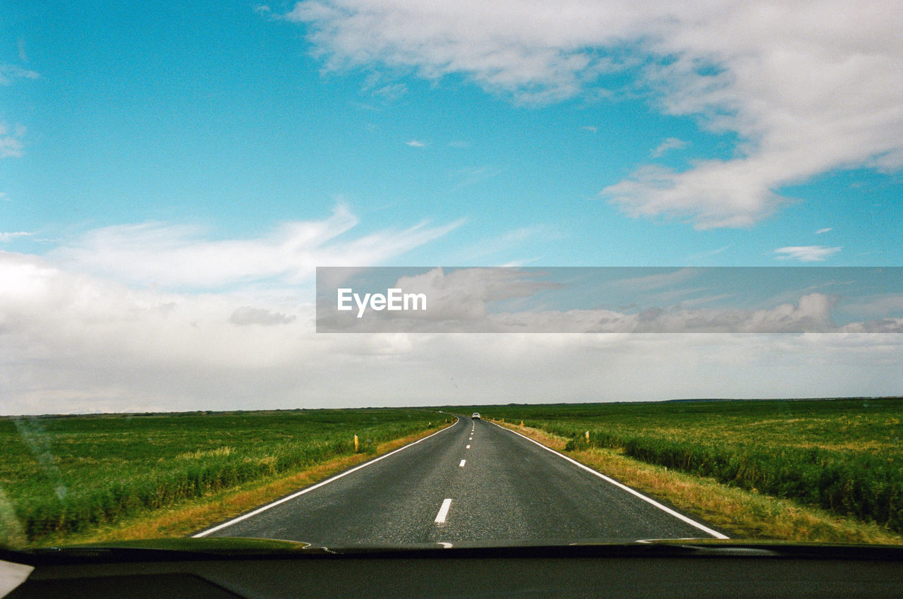 transportation, sky, horizon, road, cloud, plain, the way forward, nature, travel, landscape, windshield, mode of transportation, environment, vehicle interior, vanishing point, road trip, highway, rural scene, car, journey, diminishing perspective, horizon over land, no people, plant, grass, land, glass, field, motor vehicle, car interior, transparent, day, country road, scenics - nature, symbol, road marking, non-urban scene, prairie, motion, marking, on the move, outdoors, car point of view, sign, sunlight, hill, morning, beauty in nature, green, land vehicle, infrastructure, rural area, blue, tranquility, dividing line, travel destinations