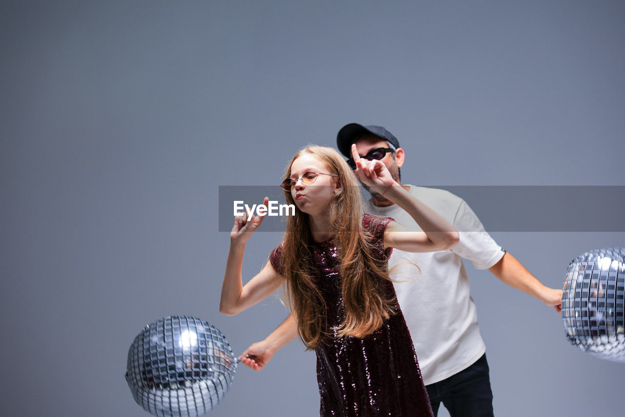A dynamic dance duo performing with colorful disco balls in a vibrant studio space