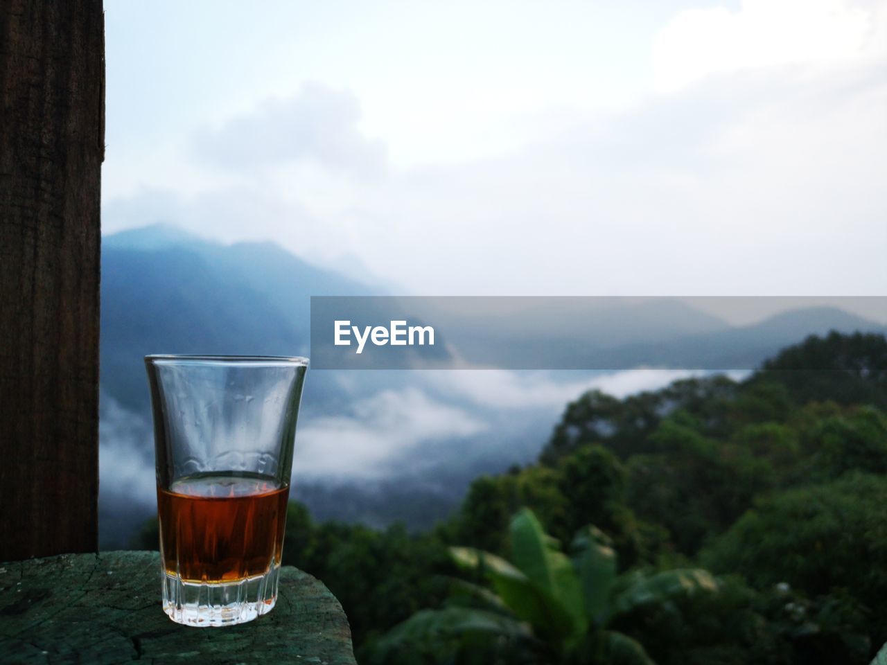 Whiskey glass on table against mountains