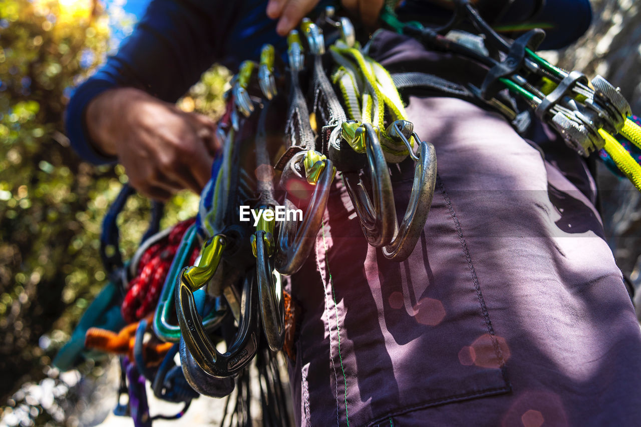 Midsection of man with safety harnesses while standing in forest