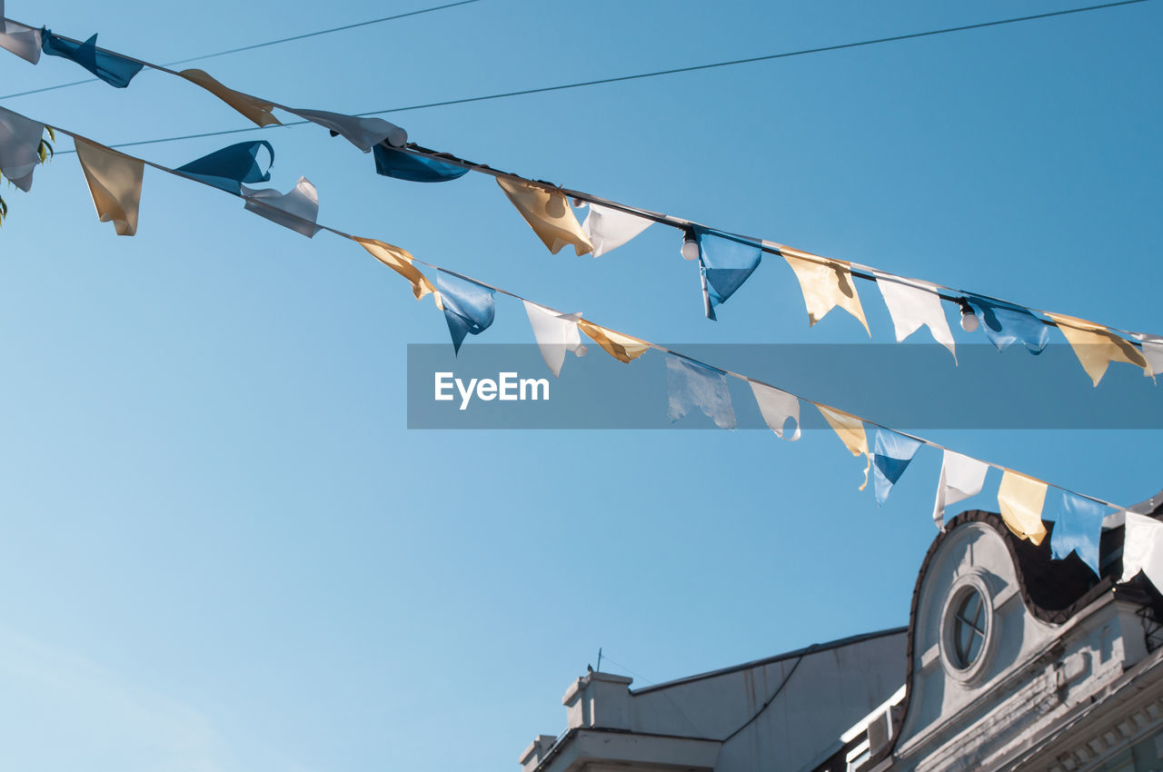 LOW ANGLE VIEW OF FLAGS HANGING AGAINST SKY