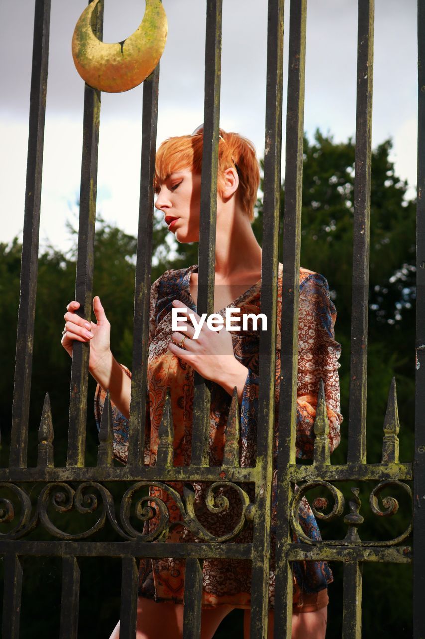 Redhead woman standing by metallic gate