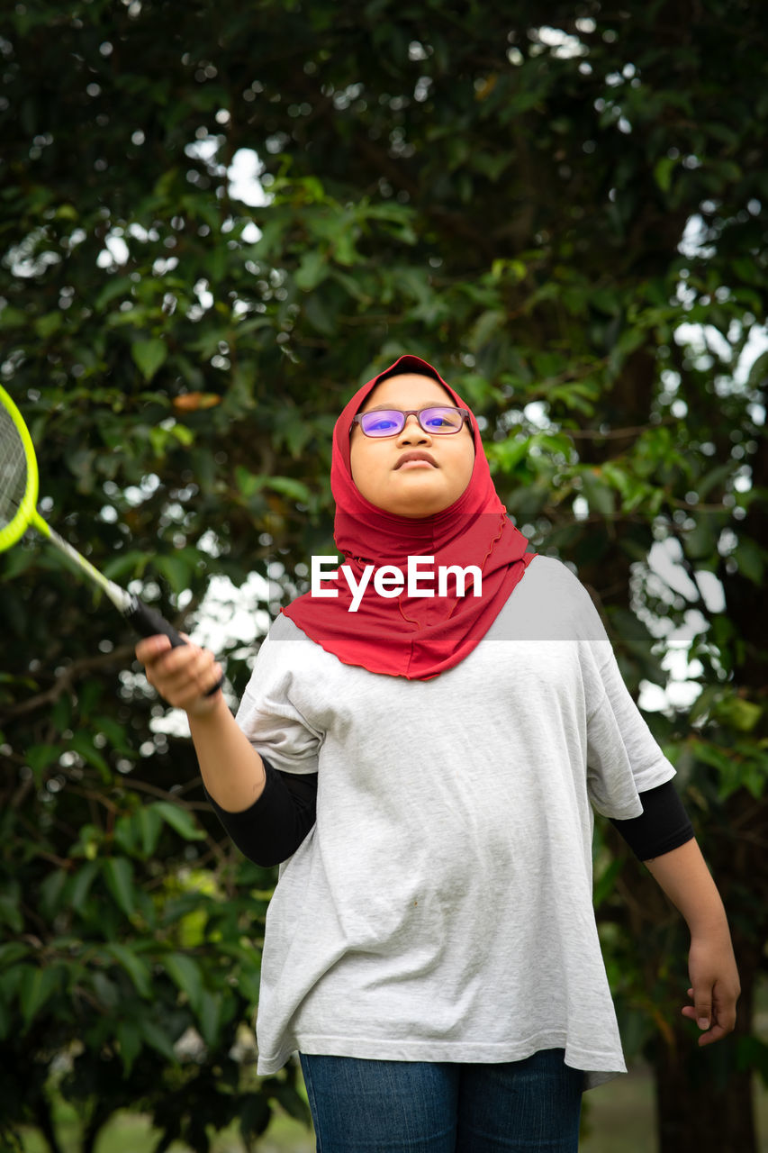 Young hijab asian girl with badminton racket at the park.