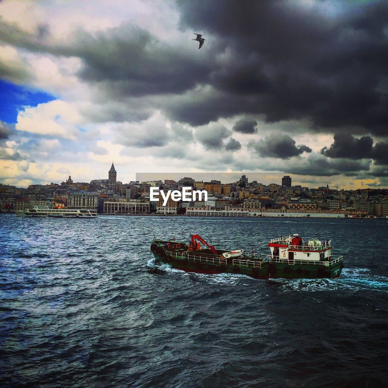 Boat on sea against cloudy sky in city