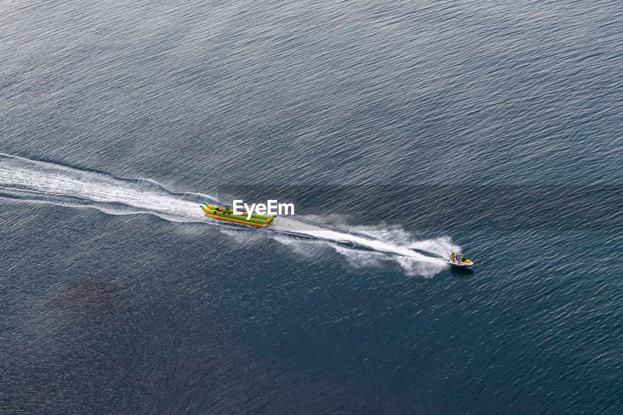 Jet ski towing on the sea inflatable banana. view from above. beautiful ripples in the sea water