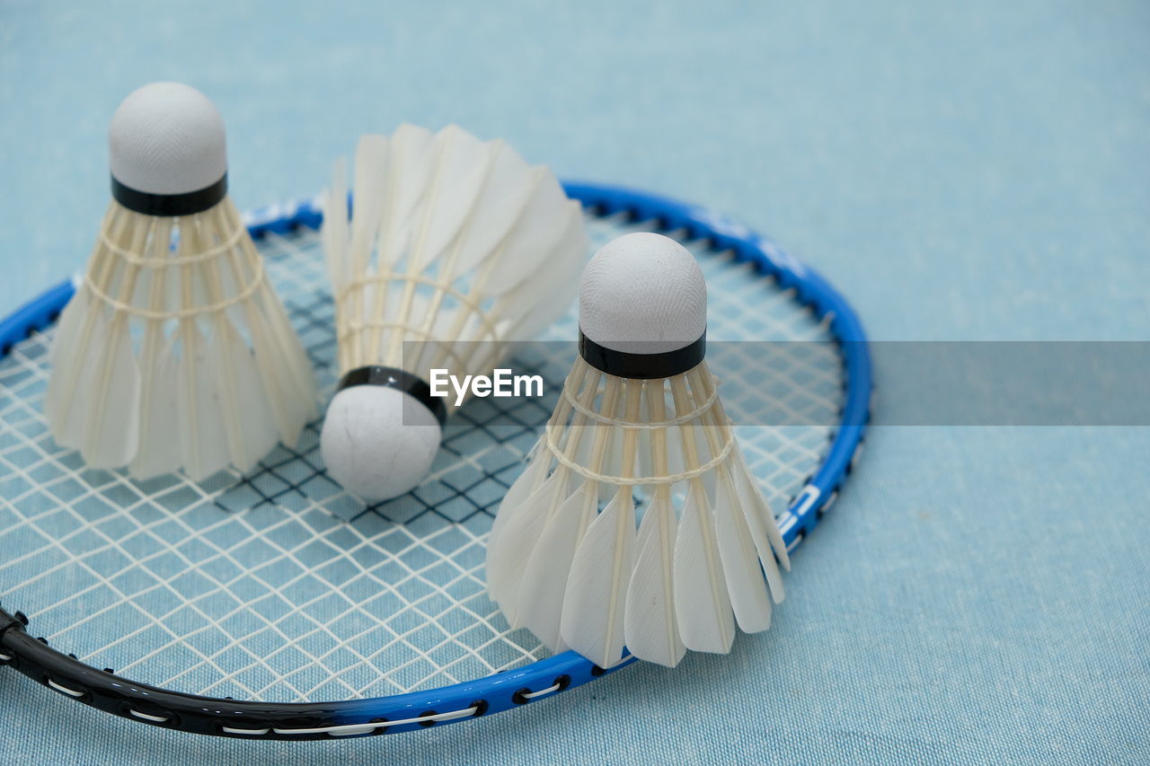 Close-up of shuttlecocks and badminton racket on table