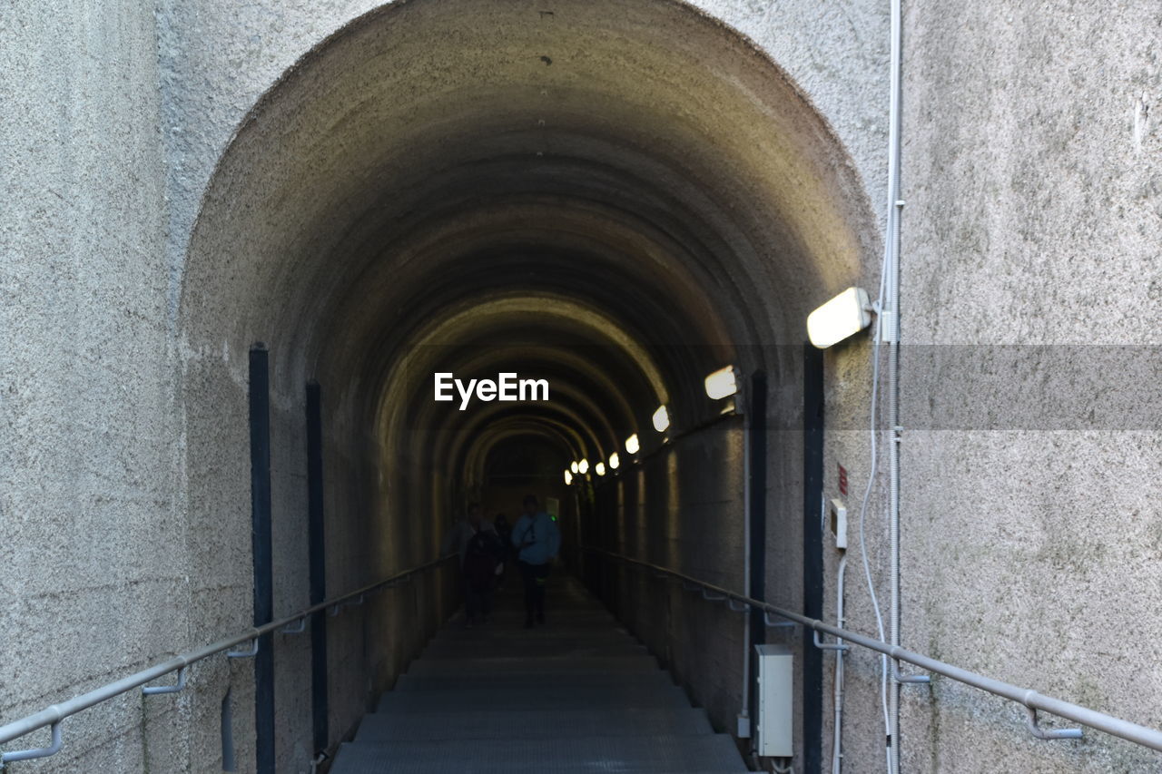 architecture, arch, built structure, tunnel, infrastructure, the way forward, wall - building feature, arcade, subway, corridor, diminishing perspective, building, one person, full length, walking, men, day, indoors, footpath, wall, adult, rear view